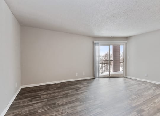 an empty living room with a sliding glass door to a balcony at Eastwood Crossings, Kansas City, MO, 64129