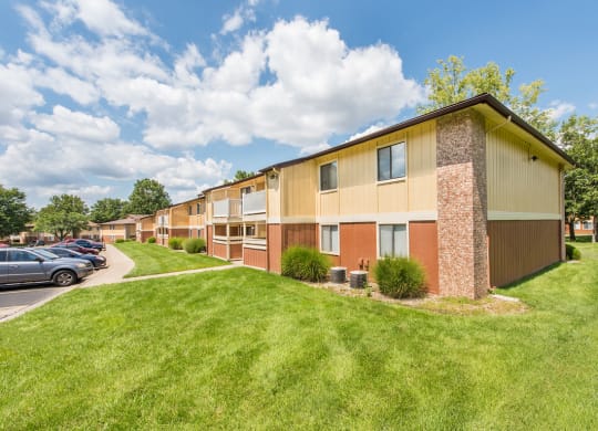 a row of apartment buildings with a green lawn and a parking lot at Lodge of Overland Park Apartments, Overland Park , KS
