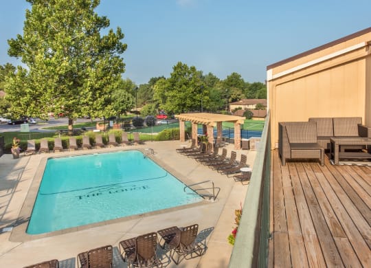 a swimming pool with chairs and a poolside deck with a fence at Lodge of Overland Park Apartments, Overland Park
