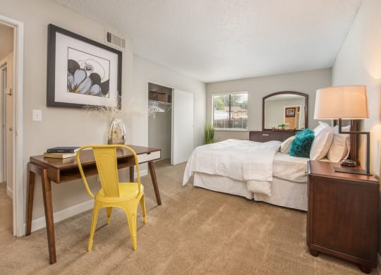a bedroom with a bed and a desk with a yellow chair at Lodge of Overland Park Apartments, Overland Park , Kansas