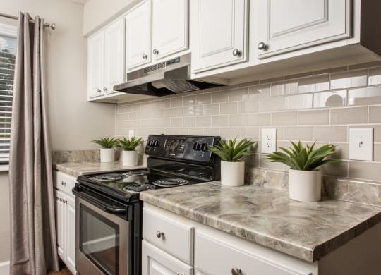 a kitchen with white cabinets and a black stove at Lodge of Overland Park Apartments, Overland Park , KS