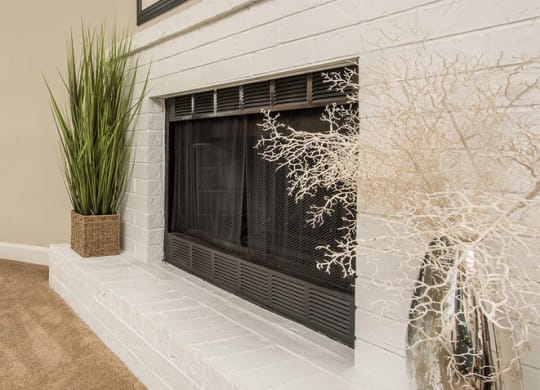 a white brick fireplace with a plant and paintings on the wall at Lodge of Overland Park Apartments, Overland Park , KS