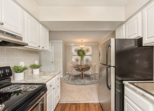 a kitchen with white cabinets and a dining room at Lodge of Overland Park Apartments, Overland Park , 66212