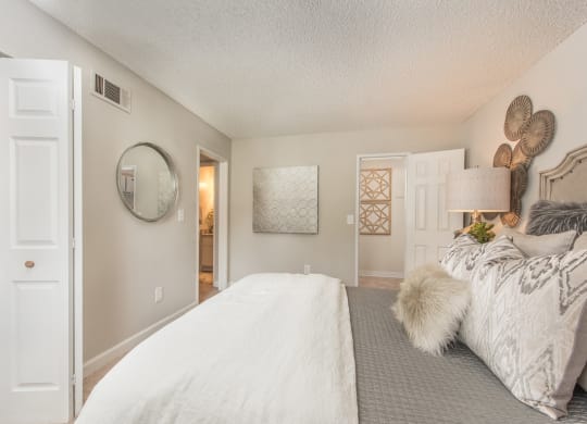 a bedroom with a large bed and a door to a bathroom at Lodge of Overland Park Apartments, Kansas