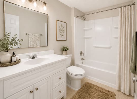 A white bathroom with a toilet, sink, and shower.