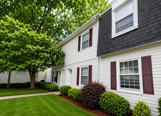 A white house with a black roof and red shutters.