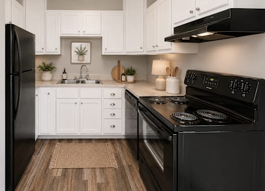 A black stove in a kitchen with white cabinets.