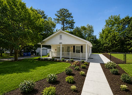 A white house with a porch and a white picket fence.
