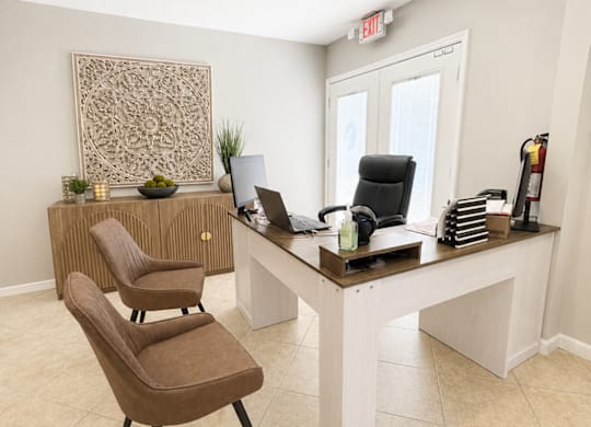 A room with a brown chair and a white desk.