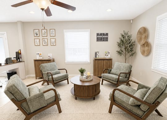 A living room with a ceiling fan and a set of chairs.