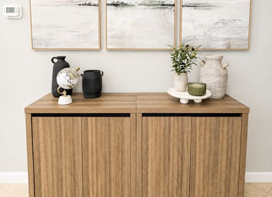 A wooden cabinet with three vases on top of it.