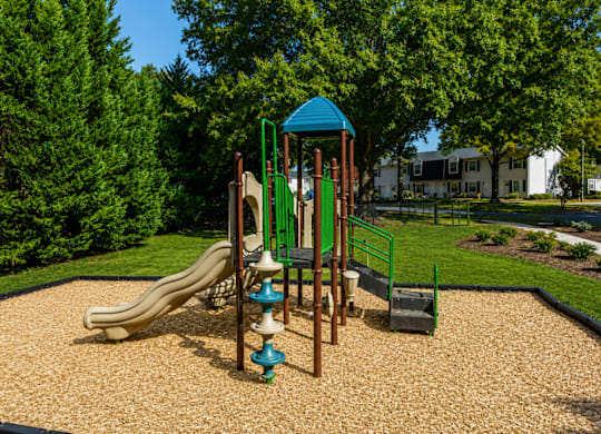 A playground with a slide, swings, and a playhouse.