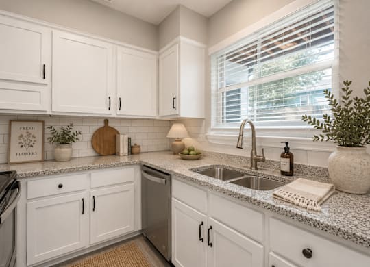A kitchen with white cabinets and granite countertops.