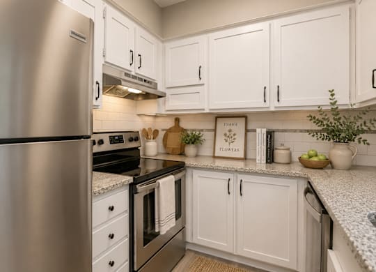 A kitchen with white cabinets and a stainless steel refrigerator.