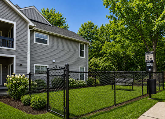 A grey house with a black fence and a sign on the tree.
