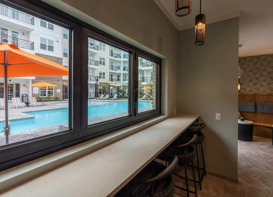 A room with a bar and a view of a pool and apartment building at Hudson at Renaissance Apartments, North Carolina 28405