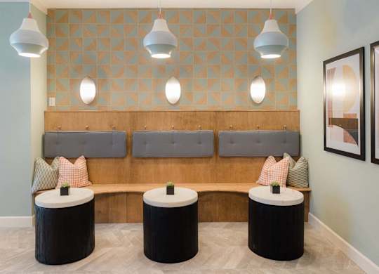 A room with a bench and three tables at Hudson at Renaissance Apartments, North Carolina