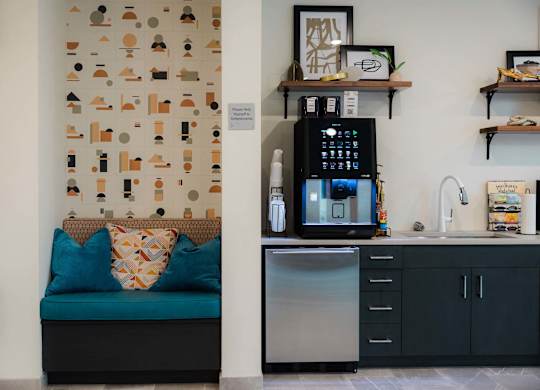 A kitchen with a blue couch and a wall with a pattern of shapes at Hudson at Renaissance Apartments, Wilmington, North Carolina