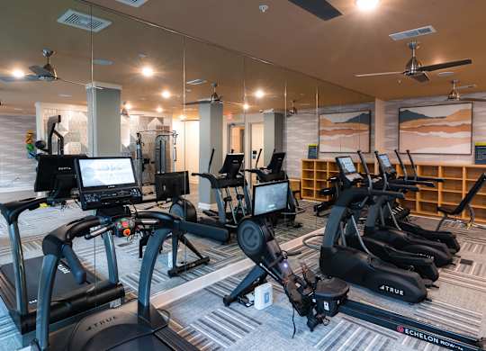 A gym with a variety of exercise equipment including treadmills and stationary bikes at Hudson at Renaissance Apartments, Wilmington, NC 28405