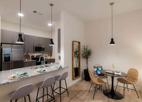 A kitchen with a bar area and a dining table with chairs at Hudson at Renaissance Apartments, Wilmington, NC