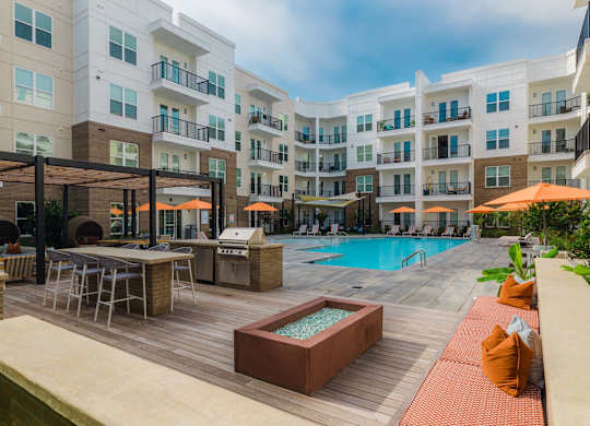 A large outdoor pool area with a hot tub and lounge chairs at Hudson at Renaissance Apartments, Wilmington, NC