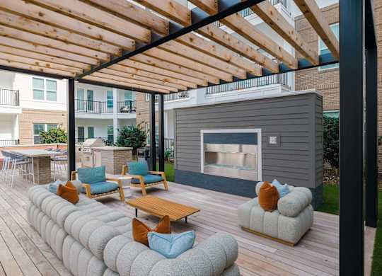 A wooden deck with a fireplace and seating area at Hudson at Renaissance Apartments, Wilmington, NC