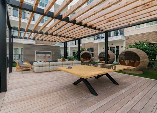 A wooden table is in the middle of a wooden deck at Hudson at Renaissance Apartments, Wilmington 28405