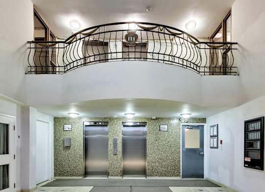 A hallway with a staircase and three elevators.