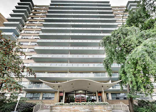 A modern building with a curved entrance and balconies on the upper floors.