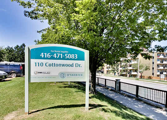 A sign for 110 Cottonwood Dr. is displayed in front of a tree.