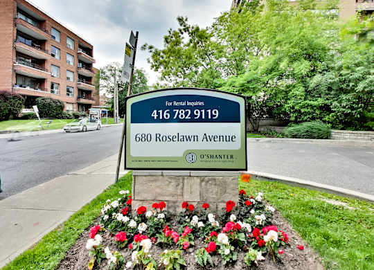 a sign on the side of a street next to some flowers