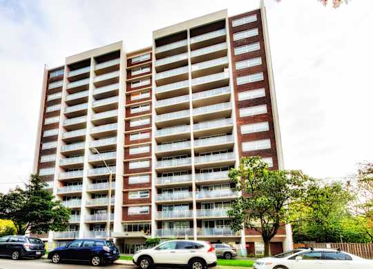 A large apartment building with cars parked in front.