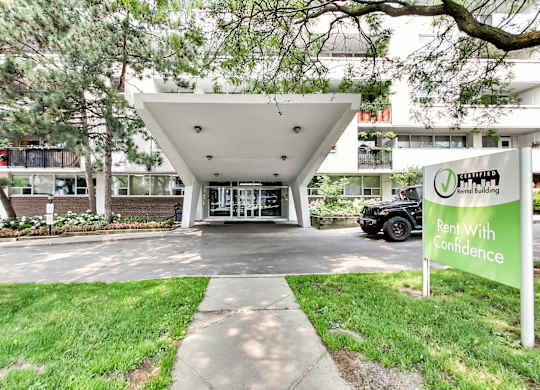 an apartment building with a green sign that says rent with confidence in front of it