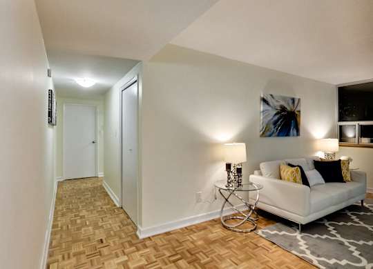 A living room with a white couch and a painting on the wall.