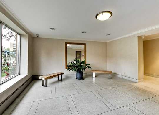 a hallway with benches and a potted plant and a large window