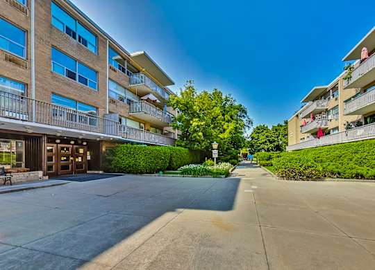 an apartment building with a sidewalk and trees in front of it