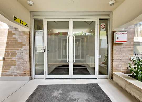 a door to a building with glass doors and a rug in front of it