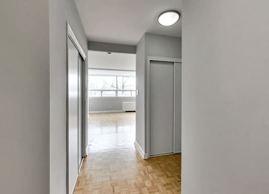 an empty living room with a window and a door to a bedroom