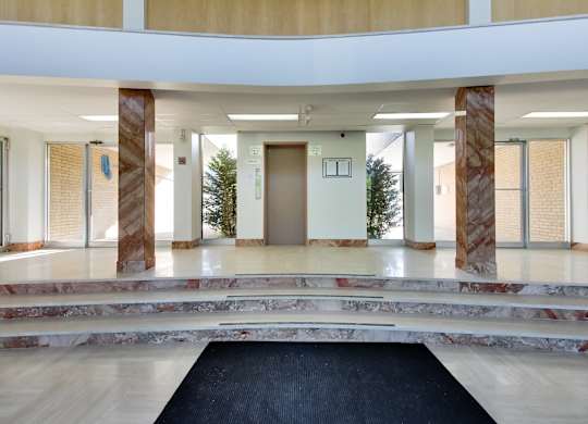 a lobby with pillars and a black rug and a door