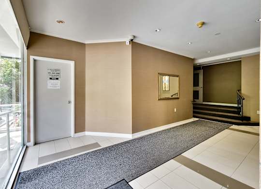 a lobby with a door and a carpeted floor and a staircase