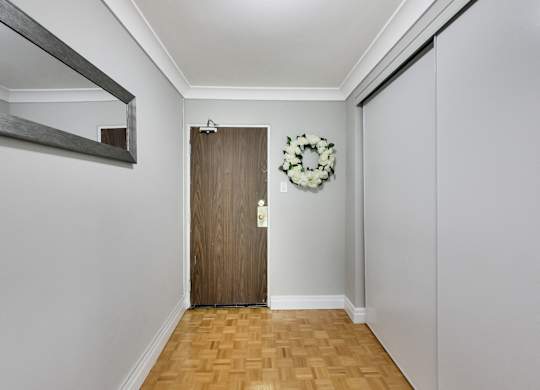 A hallway with a wooden door and a wreath on the wall.