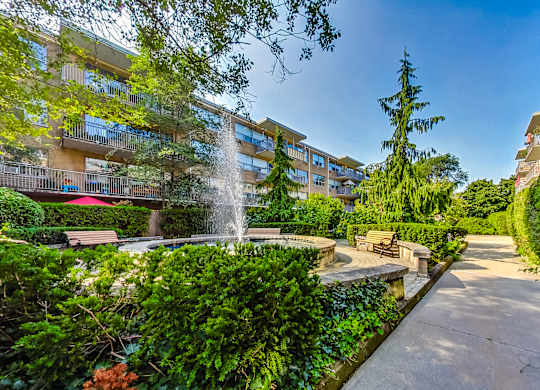 a courtyard with a fountain and benches in front of an apartment building