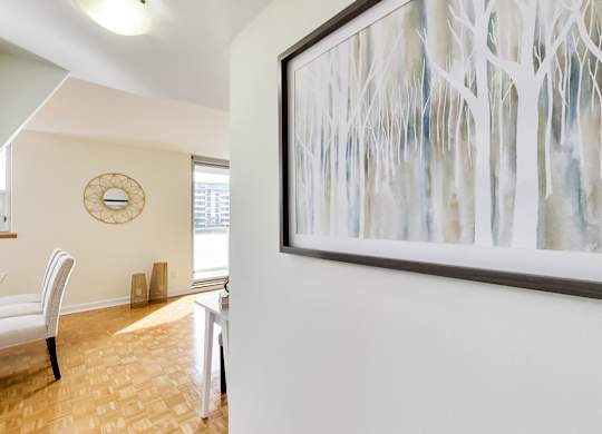 A painting of trees hangs on a wall above a table.
