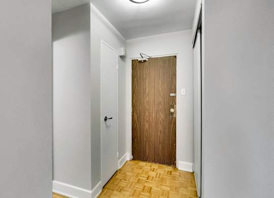 A hallway with a wooden door and a white wall.