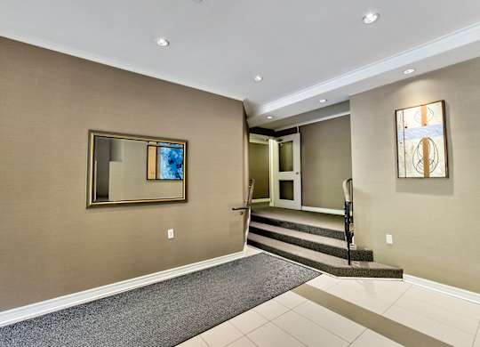 a entryway with carpet and stairs and a mirror on the wall