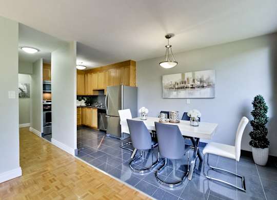 a dining room with a white table and chairs and a kitchen