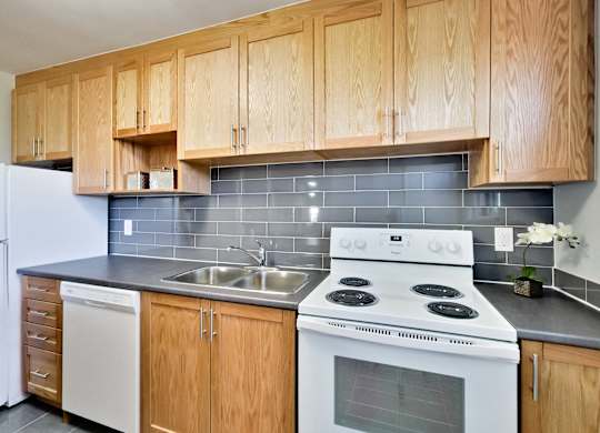A kitchen with wooden cabinets and a white stove top oven.