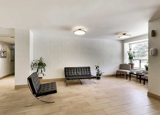 a living room with two black chairs and a table and a window