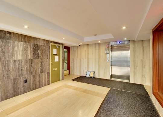 A hallway with a wooden floor and a grey carpet.