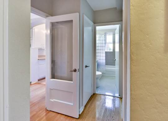 an open door leading into a bathroom with a toilet and a shower